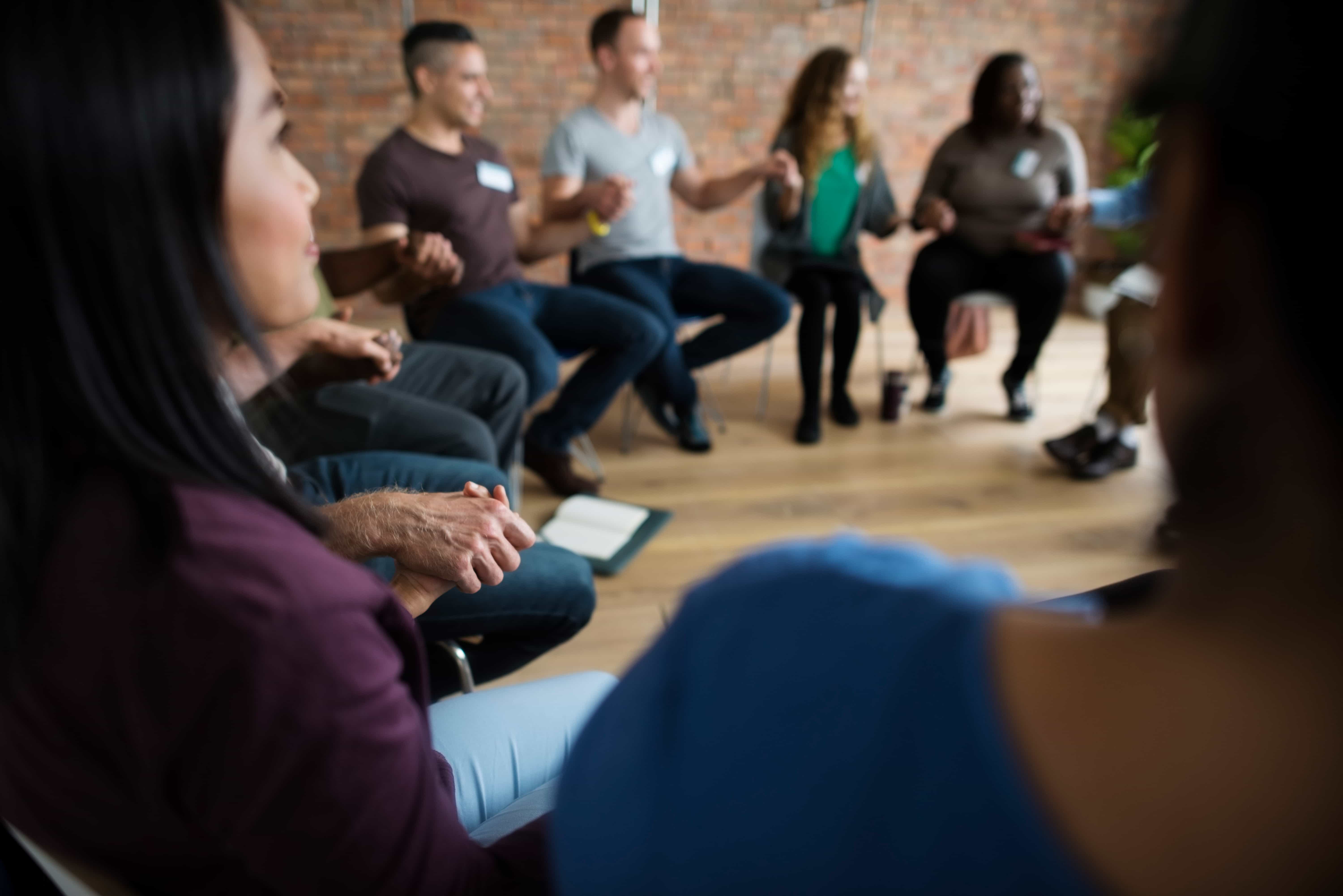 Group participants holding hands during a supportive session